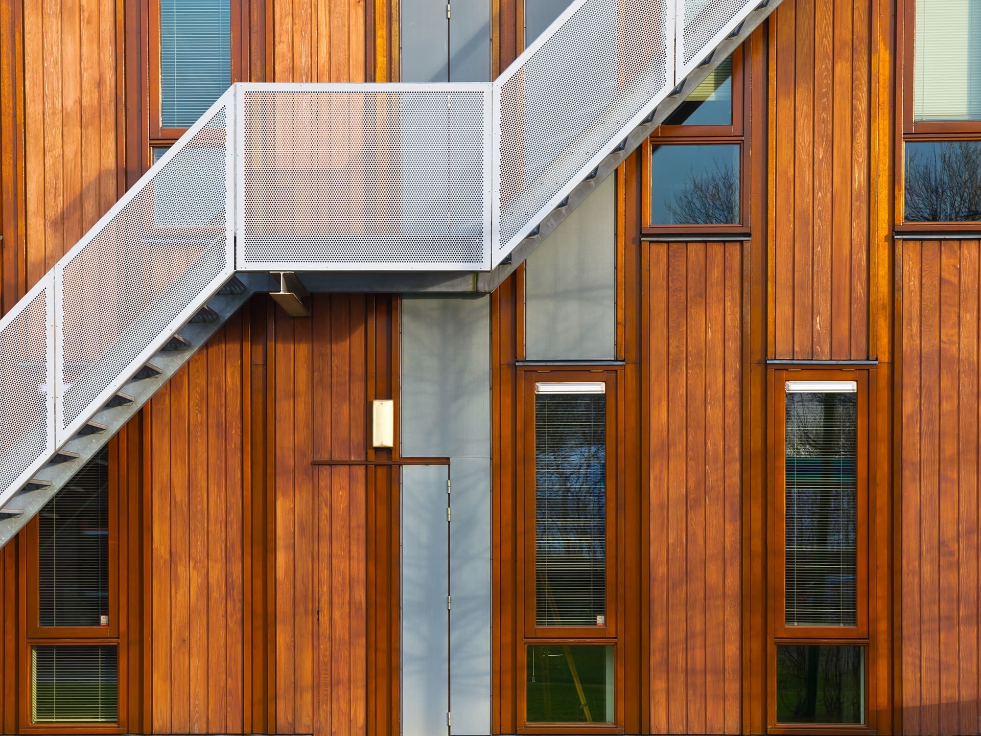 Warm wood-clad residential facade with exterior stair