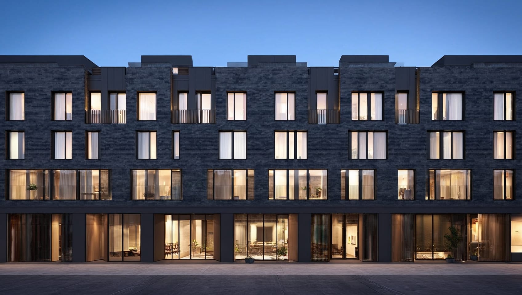 Night exterior photograph of a modern six-storey apartment building with charcoal brickwork and dramatic accent lighting